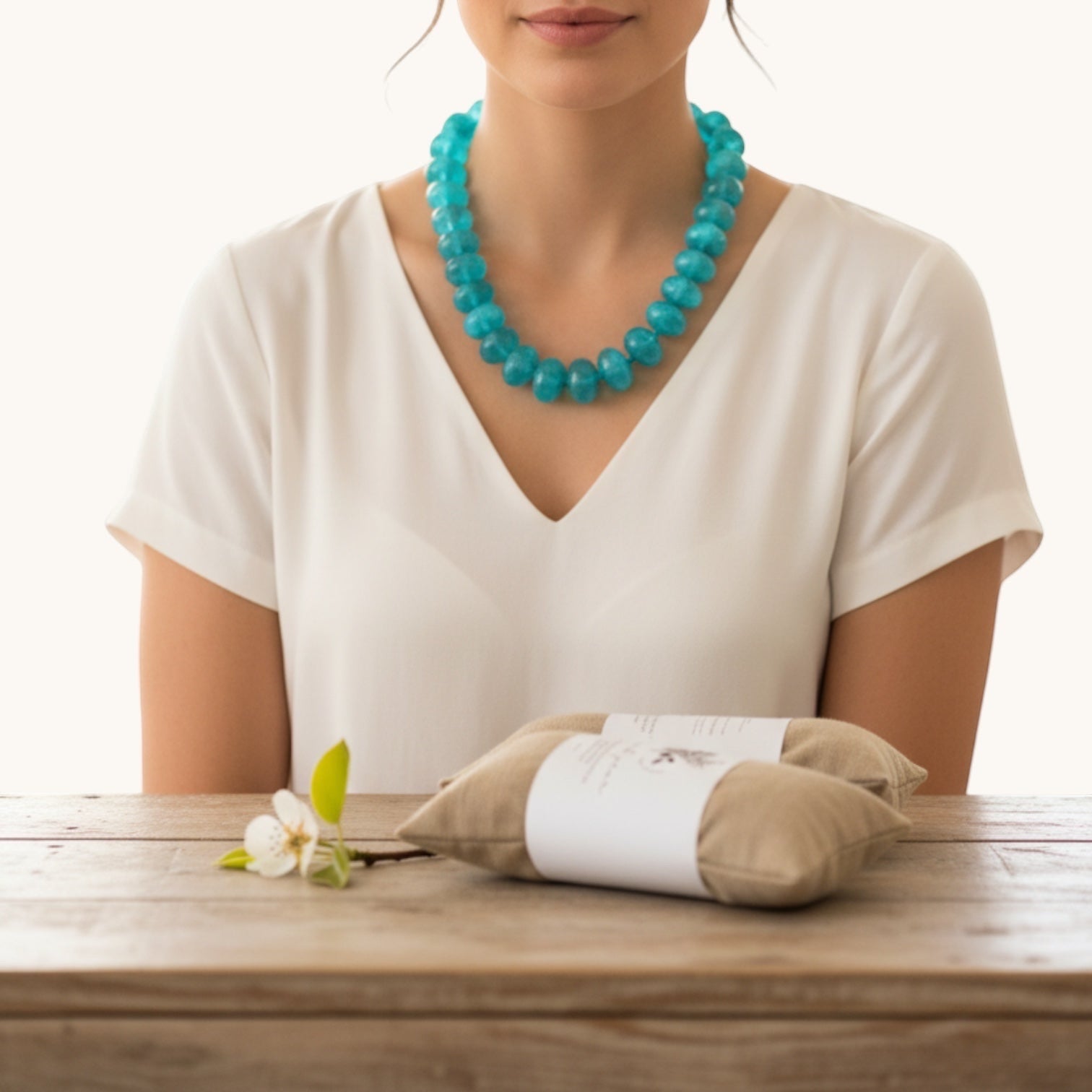 Home-Industry South Africa aqua blue glossy resin bead necklace on a woman wearing a white v-neck shirt.