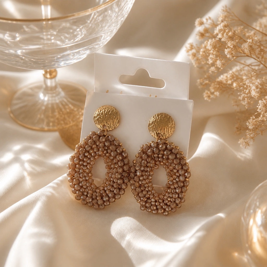 Home-Industry South Africa champagne beaded oval statement earrings with hammered gold studs on a silk background.